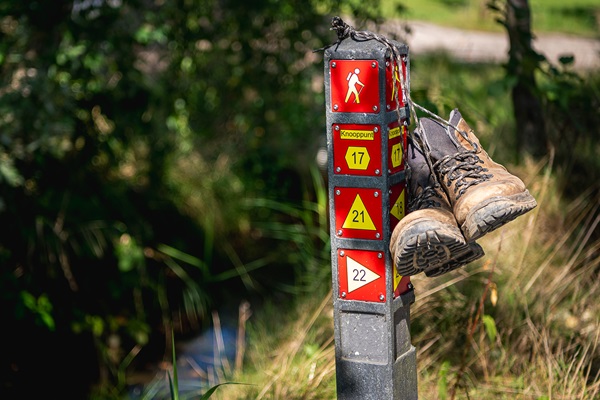 Wandelschoenen hangen aan een routepaal in de gemeente Roermond